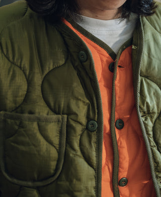 Olive quilted jacket close-up with button placket and ribbed collar
