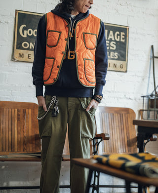 Orange quilted padded vest with button front and patch pockets, styled with work pants