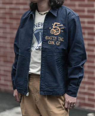 Navy tour jacket with front zip, chest pocket, and embroidered badge graphic