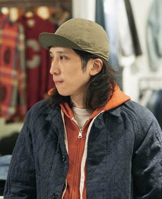 Olive nylon cap with adjustable rear strap, worn back-to-side view