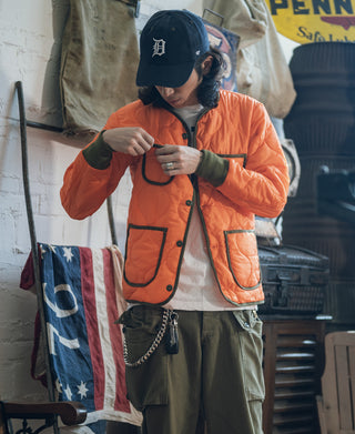 Orange quilted padded ripstop jacket with button front and flap pockets, worn by model