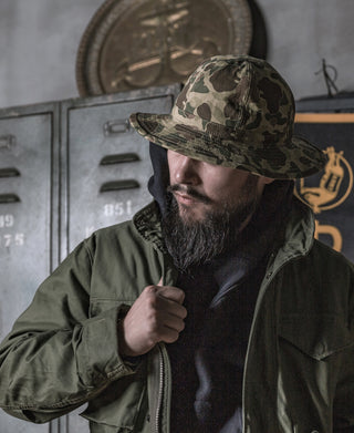 Man wearing a camo bucket hat with chin strap and brim shadow