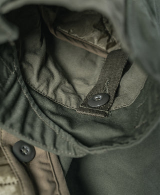 Olive jacket liner detail with snap-secured collar tab and stitched seam