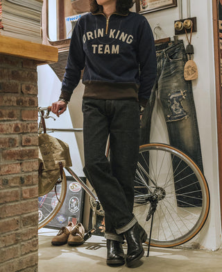 Indigo selvedge denim jeans worn with boots and dark leather jacket, full length view