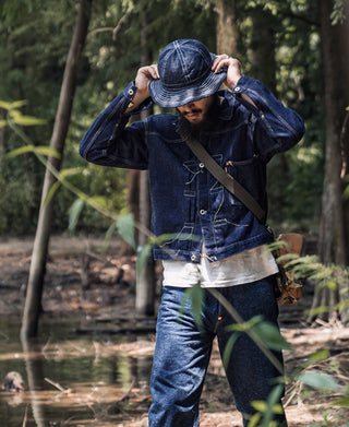 Indigo denim bucket hat with wide brim and stitched paneling, worn outdoors