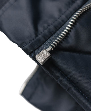 Navy jacket sleeve cuff with metal zipper pull and quilted fabric seam