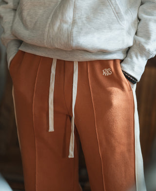 Orange sweatpants with white drawstrings and small logo embroidery at hip