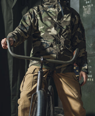 Woodland camo parka with hood up, front zipper, and drawstring waist.