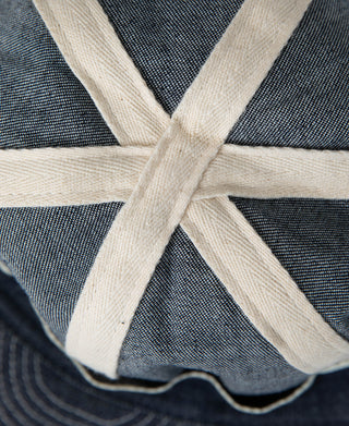 Indigo denim A-3 style cap crown with off-white cross straps and stitched lines