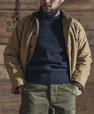 Navy crewneck wool sweater under tan jacket, ribbed knit long sleeves