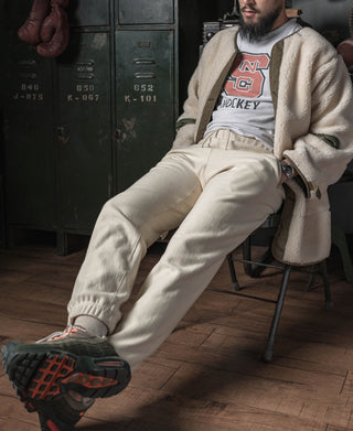 Light cream sweatpants with ribbed cuffs and sneakers; full leg view