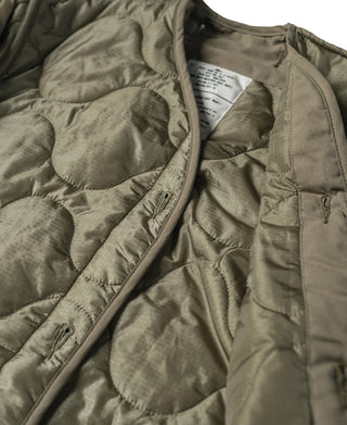 Olive quilted jacket liner close-up with central zipper and chest label tag
