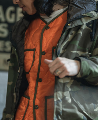 Orange quilted padded ripstop jacket detail with dark buttons and trim pocket