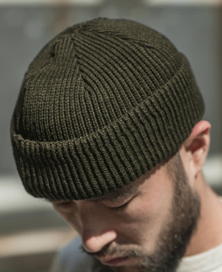 Olive knit watch cap on model, ribbed cuff and short beanie fit