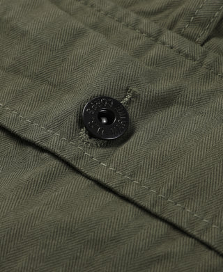 Close-up of olive shorts fabric texture with black button on flap