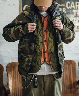 Olive quilted padded jacket with button front, ribbed cuffs, and patch pockets
