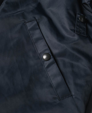 Navy jacket front placket with snap buttons and rectangular chest pocket