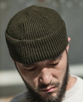 Olive knit watch cap on model, ribbed brim folded down
