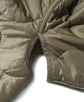 Olive quilted jacket liner close-up of side seam and curved quilt panels