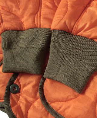 Orange quilted padded jacket with dark ribbed knit cuffs and buttoned pocket flap