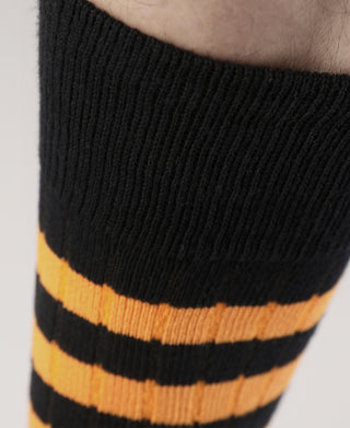 Close-up of black sock cuff with orange-and-black horizontal stripes.