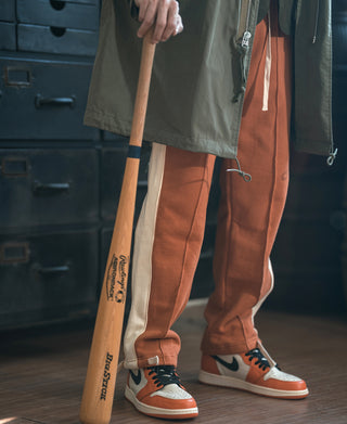 Orange sweatpants with drawstring and hip logo, worn with sneakers and light-blue trim