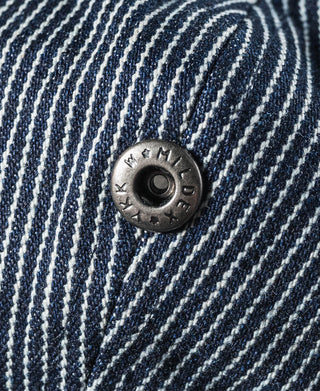 Striped denim newsboy cap button detail, dark blue-and-white pinstripes with metal snap.